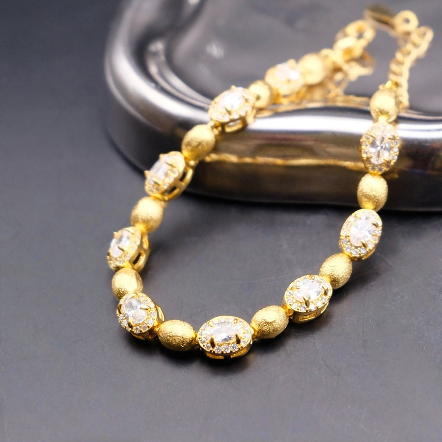 Bracelet: gold-coloured brushed oval beads alternating with oval clear stones in halos