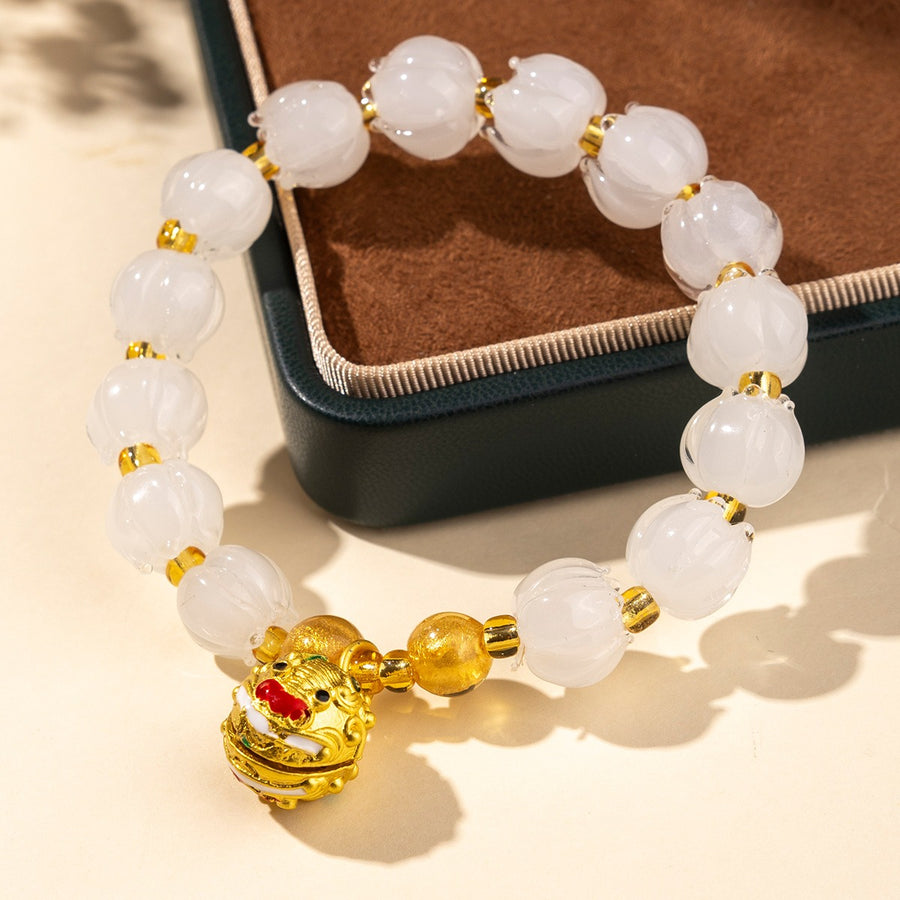 Bracelet: translucent pale white lotus-shaped liuli glass beads with a gold-coloured Tunjin beast charm