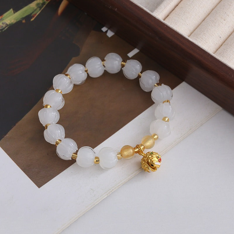 Bracelet: translucent pale white lotus-shaped liuli glass beads with a charm, third view