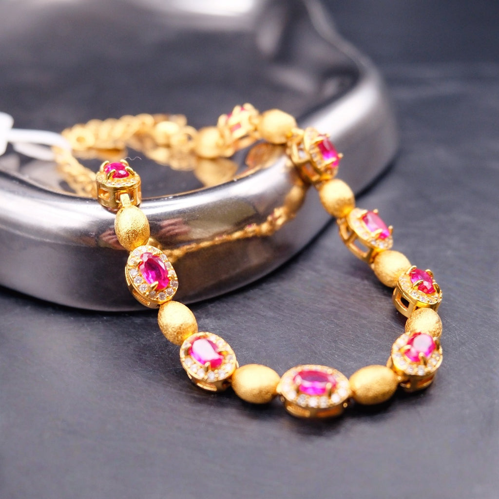 Bracelet: gold-coloured brushed oval beads alternating with oval pink-red stones in clear halos