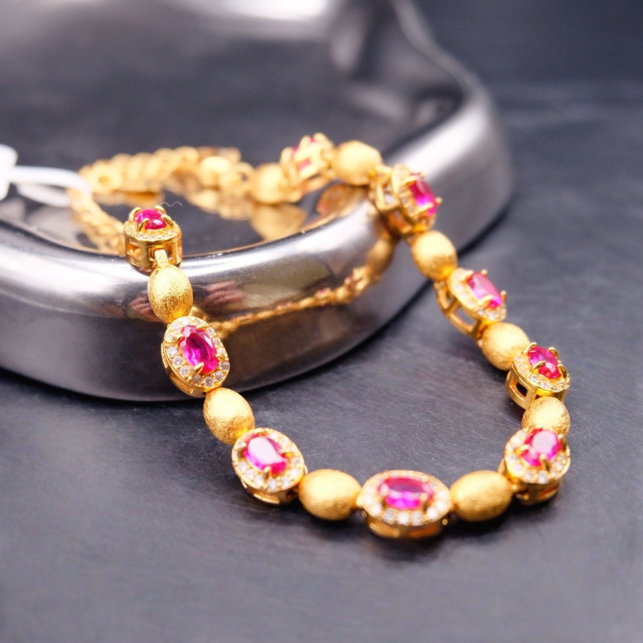 Bracelet: gold-coloured brushed oval beads alternating with oval pink-red stones in clear halos