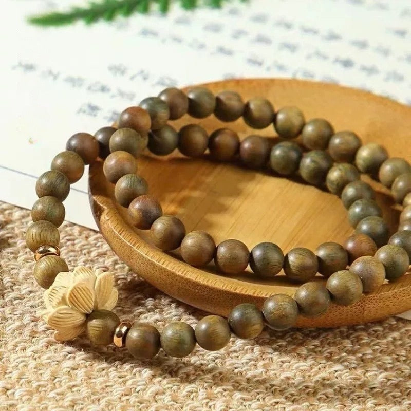 Bracelet: double wrap of green-brown sandalwood beads with a cream carved boxwood lotus