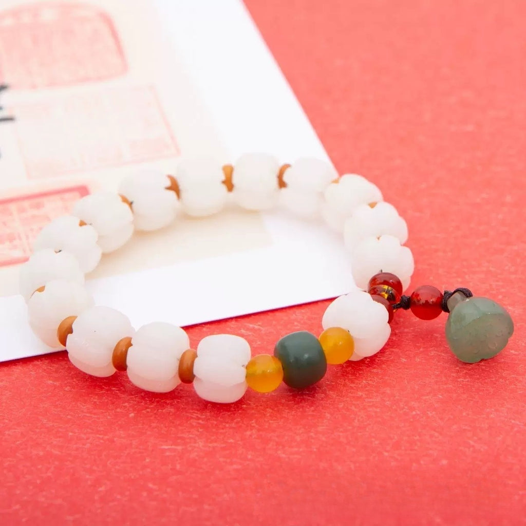 Bracelet: white pumpkin-shaped bodhi root beads with yellow, green and red accent beads and a pale green charm