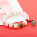 Bracelet: white pumpkin-shaped bodhi root beads with yellow, green and red accent beads and a pale green charm