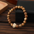 Bracelet: light brown green sandalwood beads with a cream carved boxwood lotus bead