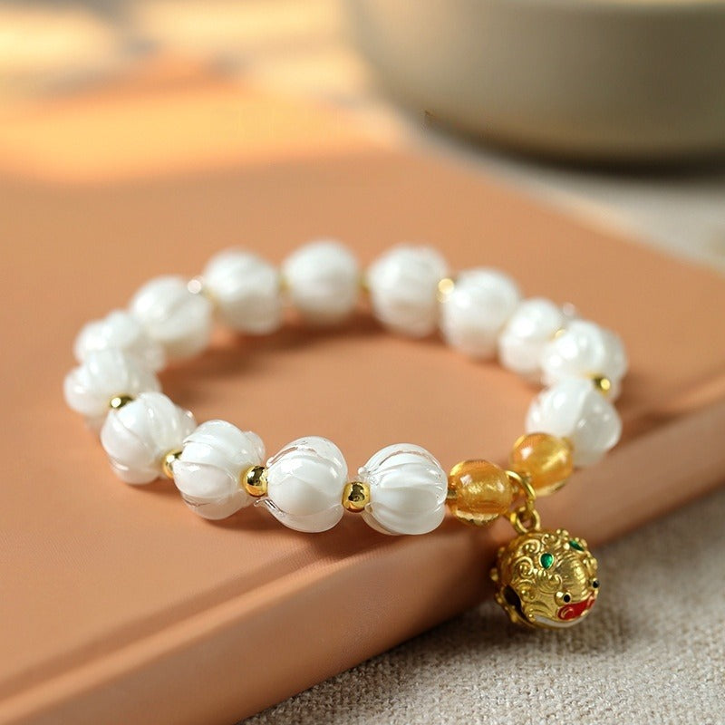 Bracelet: milky white lotus-shaped liuli glass beads with a gold-coloured Tunjin beast charm