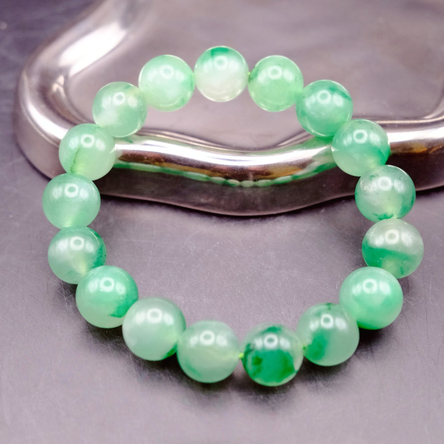 Bracelet: round translucent green African Jade beads resting on a metal tray