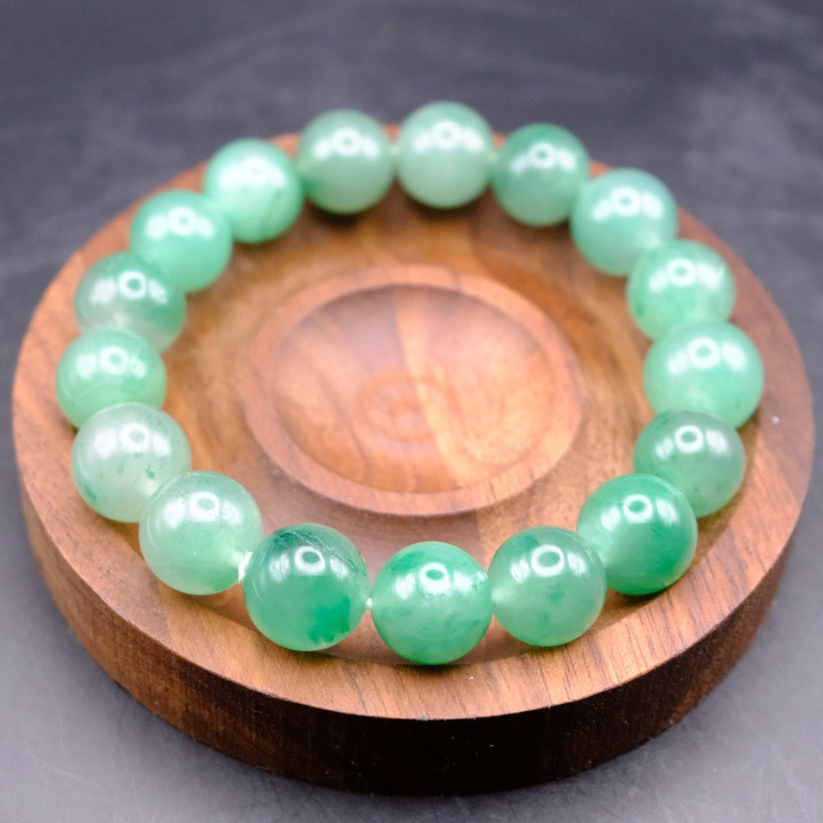 Bracelet: round green African Jade beads on a wooden dish