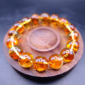 Bracelet: transparent golden-orange amber beads with flower-like inclusions, on a wooden dish
