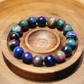 Bracelet: pietersite beads with blue, violet and green shimmering bands, in a wooden dish