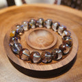 Bracelet: clear phantom quartz beads with red-brown inclusions, in a wooden dish