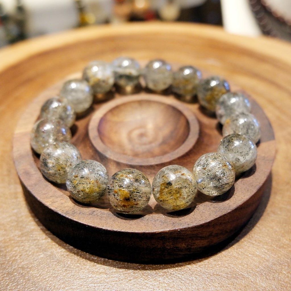 Bracelet: Super Seven beads, clear grey with dark and golden inclusions, in a wooden dish
