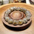 Bracelet: Super Seven beads, clear grey with dark and golden inclusions, in a wooden dish