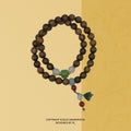 Wrap bracelet: two loops of dark brown sandalwood beads with green, white and red accent beads and a green charm