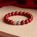 Bracelet: round deep crimson cinnabar beads with a lotus-shaped metal bead and one pale pink bead
