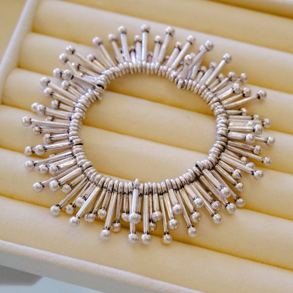Bracelet: sculptural polished 925 sterling silver bracelet of radiating tubes with ball ends, on a cream tray