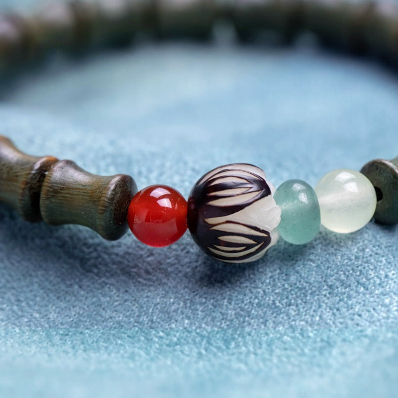 Bracelet: sandalwood beads shaped like bamboo segments, with a red cinnabar bead, third view