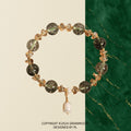 Bracelet: dark green phantom quartz beads with small crystal chips and a white baroque pearl drop