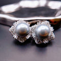 Earrings: two grey cultured Tahitian pearls in flower-shaped halos of clear stones, 925 sterling silver setting