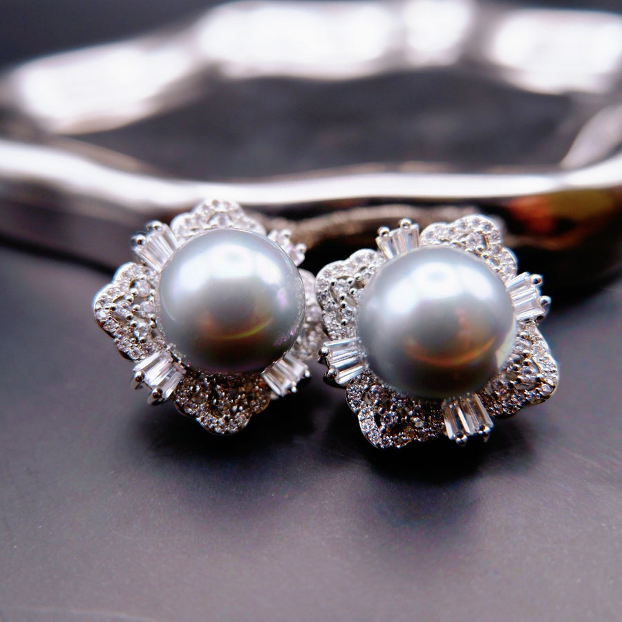 Earrings: two grey cultured Tahitian pearls in flower-shaped halos of clear stones, 925 sterling silver setting