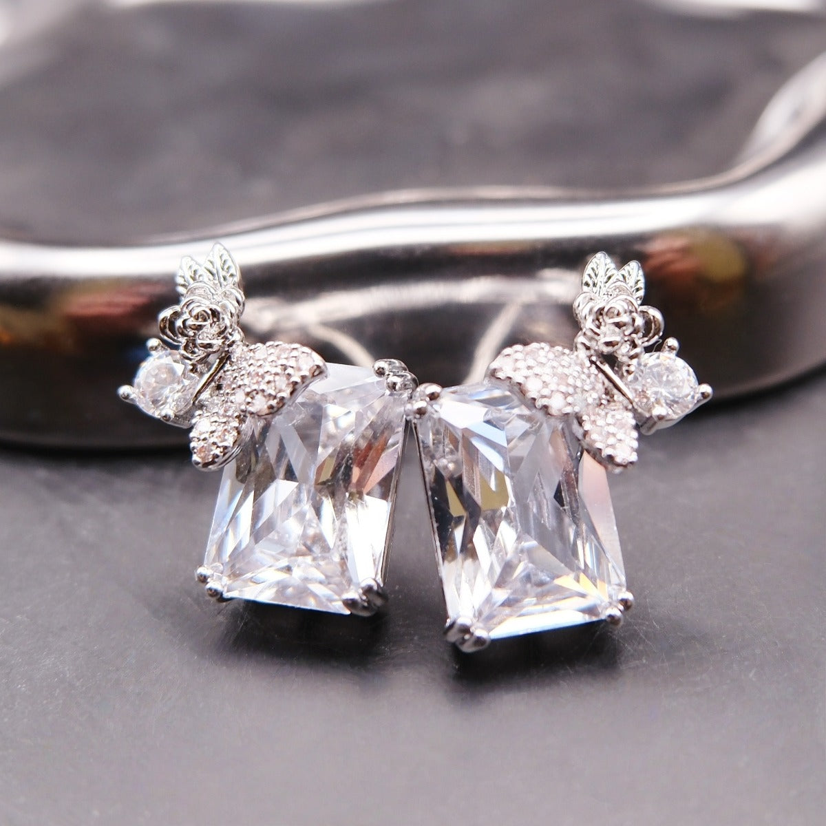 Earrings: clear emerald-cut stones topped with butterfly and flower motifs, 925 sterling silver setting