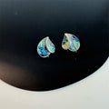 Earrings: iridescent green-blue mother-of-pearl teardrops in a silver frame, forming a heart shape