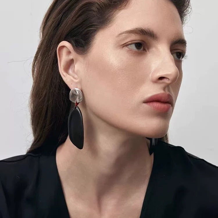 Earrings: long dark wood drops hung by red thread from round studs, second view