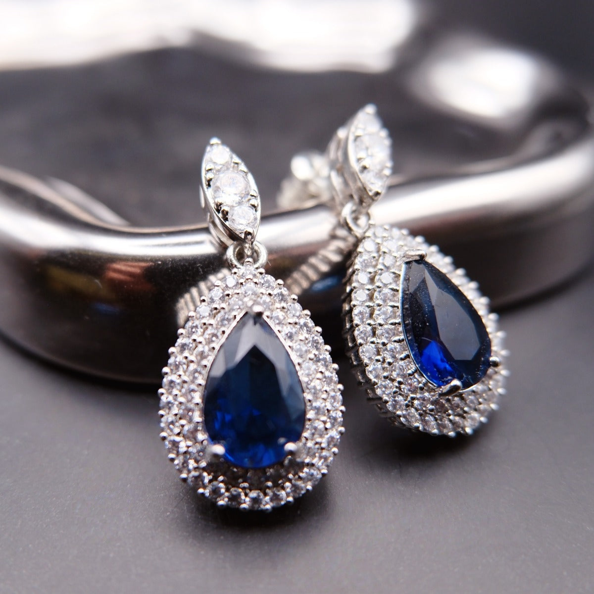 Earrings: royal blue pear-cut stones in double halos of clear stones, 925 sterling silver setting