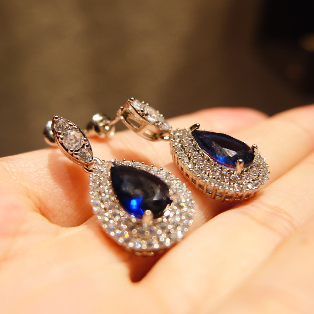 Earrings: royal blue pear-cut stones in halos of lab-created cubic zirconia, fourth view