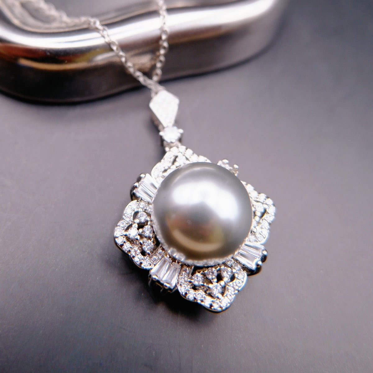 Necklace: grey cultured Tahitian pearl in a flower-shaped halo of clear stones, 925 sterling silver setting, on a chain