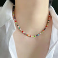 Necklace: strand of small multi-coloured stone beads, worn at the neck with a white shirt