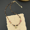 Necklace: small brown stone beads with pink and black accent beads and a gold-coloured elephant charm
