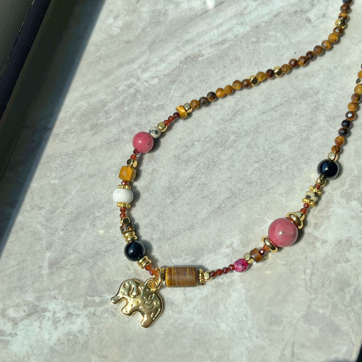 Necklace: brown gemstone beads with pink and black accents and an elephant charm, fourth view