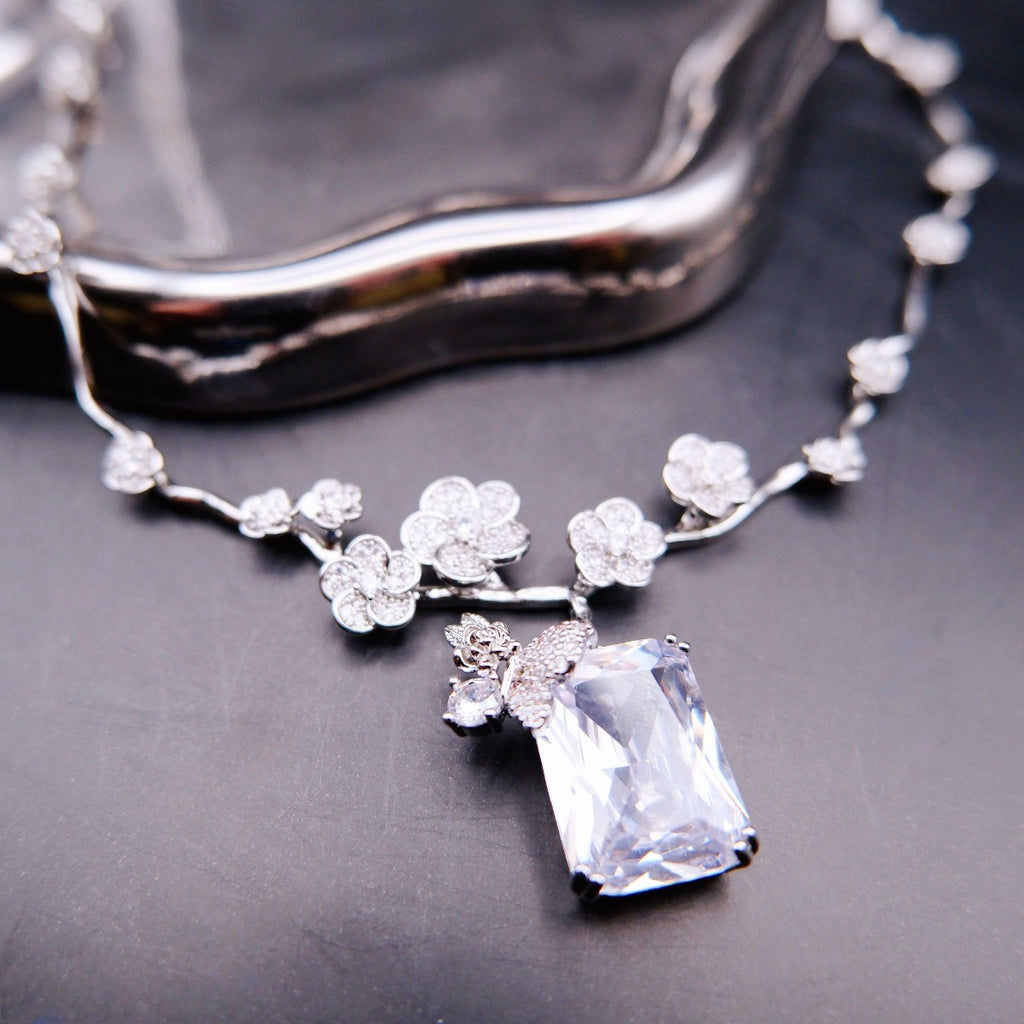 Necklace: clear emerald-cut stone below a butterfly on a 925 sterling silver floral vine chain