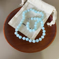 Necklace: round pale blue amazonite beads lying on a cotton pouch in a wooden dish