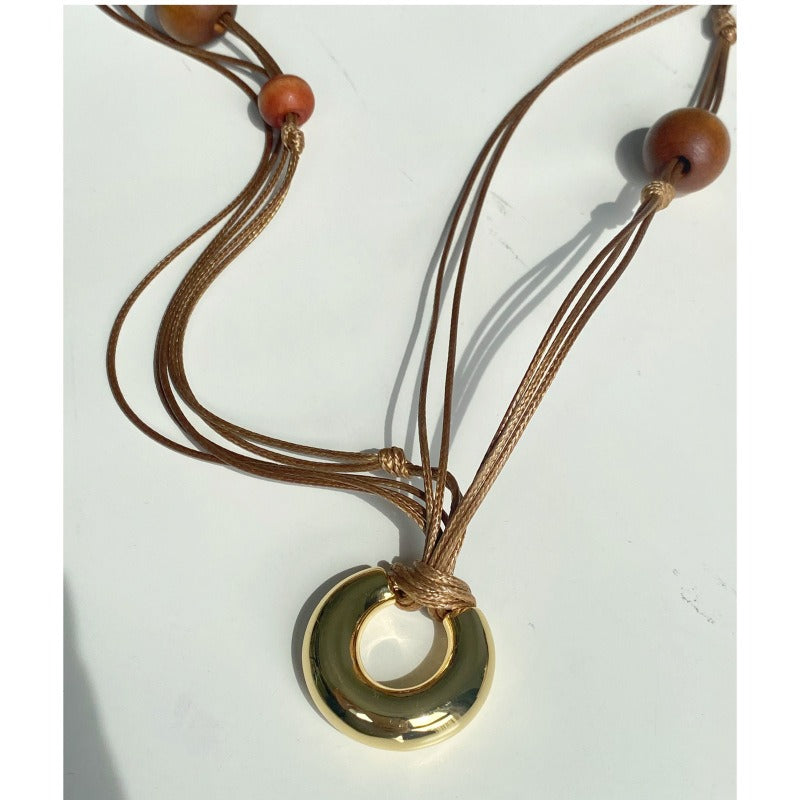 Necklace: layered brown leather cords with wood beads and a gold-tone ring, second view