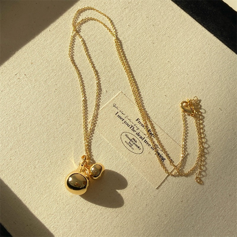 Necklace: long 18K gold plated chain with two rounded drop pendants, on a cream card