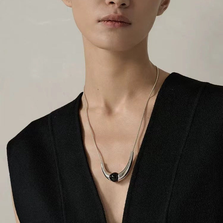 Necklace: round black agate bead held in a polished curved arc, fifth view