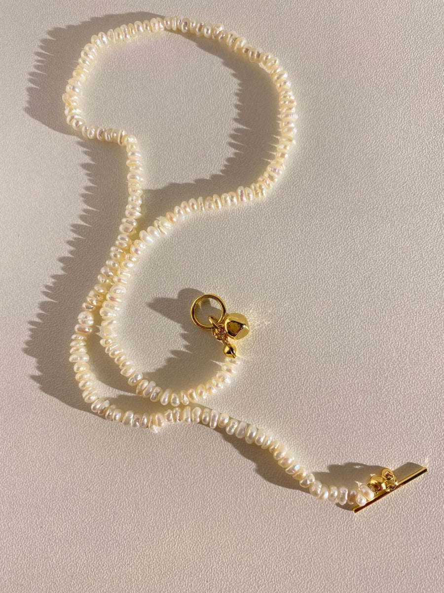 Necklace: strand of small ivory rice pearls with a gold-tone toggle clasp