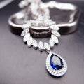 Necklace: royal blue pear-cut stone in a halo pendant on a chain of marquise clear stones, 925 sterling silver