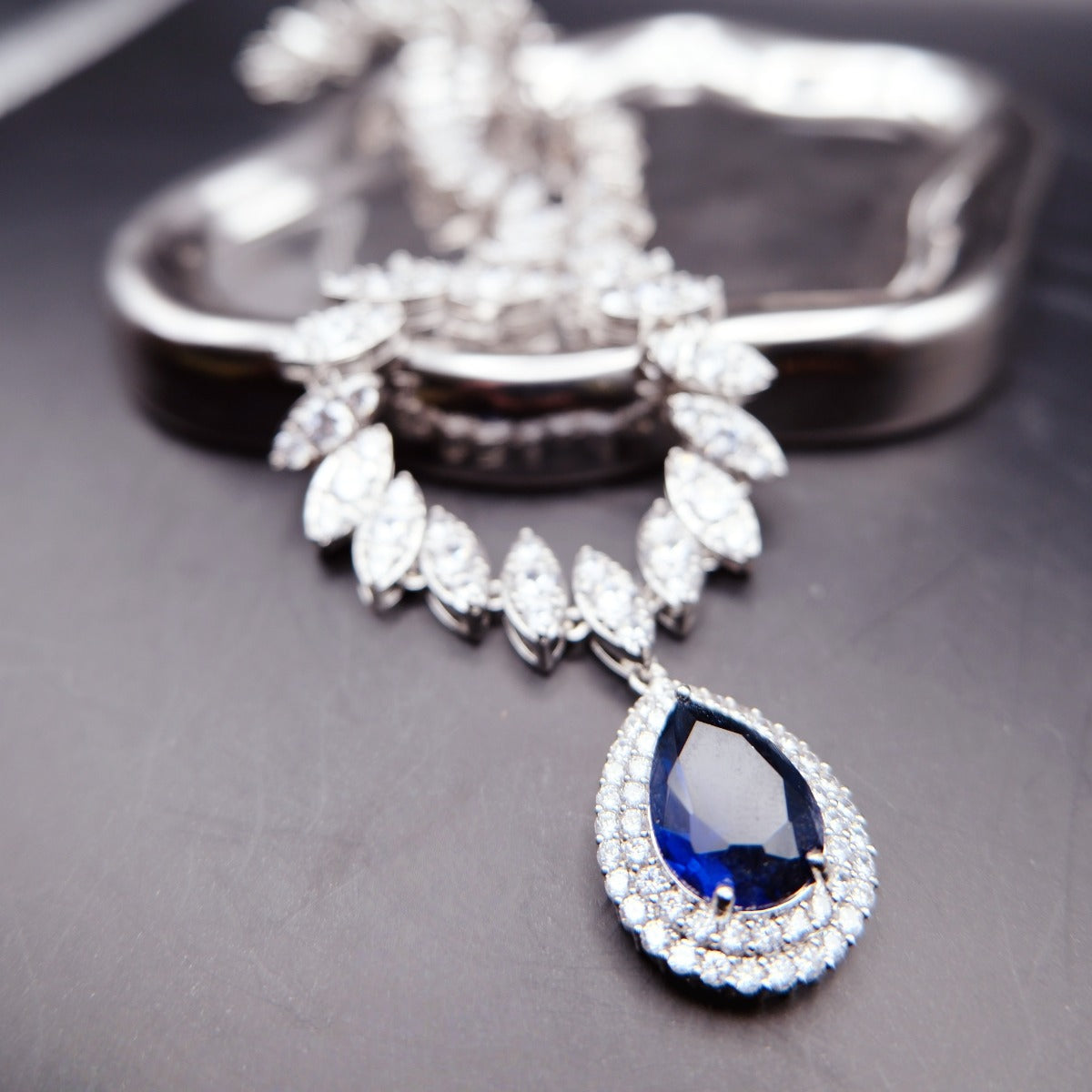 Necklace: royal blue pear-cut stone in a halo pendant on a chain of marquise clear stones, 925 sterling silver