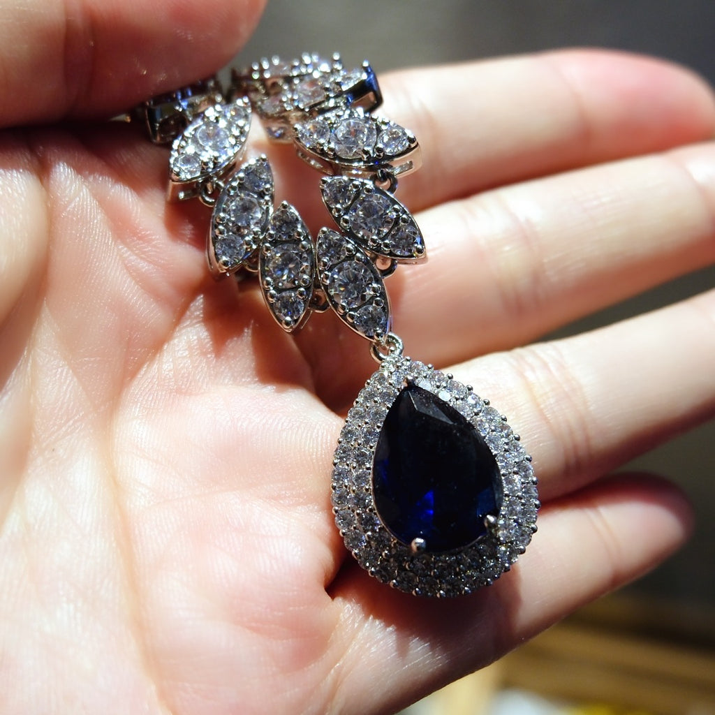Necklace: royal blue pear-cut stone in a halo pendant on a marquise-stone chain, fourth view