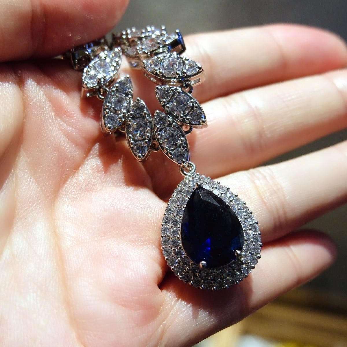 Necklace: royal blue pear-cut stone in a halo pendant on a marquise-stone chain, fourth view