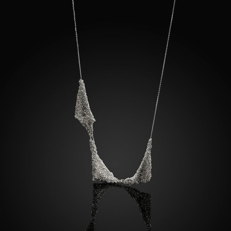 Necklace: handwoven silver mesh draped on a fine chain against a black background