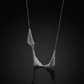 Necklace: handwoven silver mesh draped on a fine chain against a black background