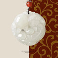 Pendant: white Hetian jade round medallion carved with a Pixiu, topped with a red bead