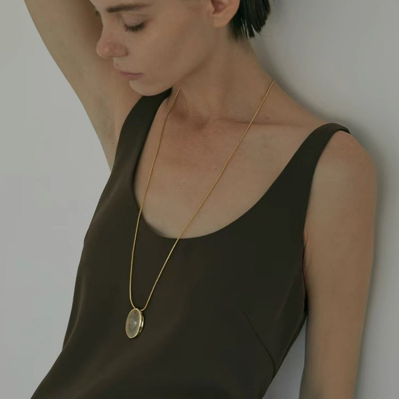 Pendant necklace: oval rutilated quartz cabochon in a gold-tone setting, third view
