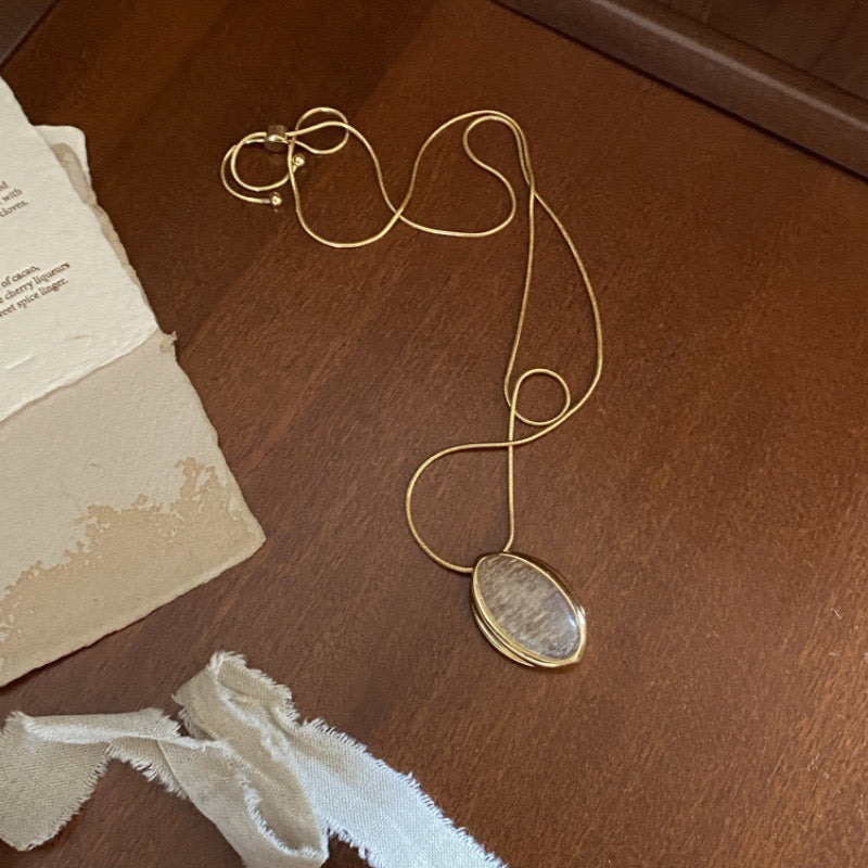 Pendant necklace: oval rutilated quartz cabochon in a gold-tone setting, fourth view