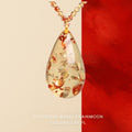 Pendant necklace: clear pale yellow floral amber teardrop with red-orange flake inclusions on a bead strand
