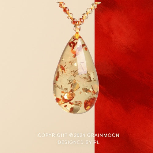 Pendant necklace: clear pale yellow floral amber teardrop with red-orange flake inclusions on a bead strand